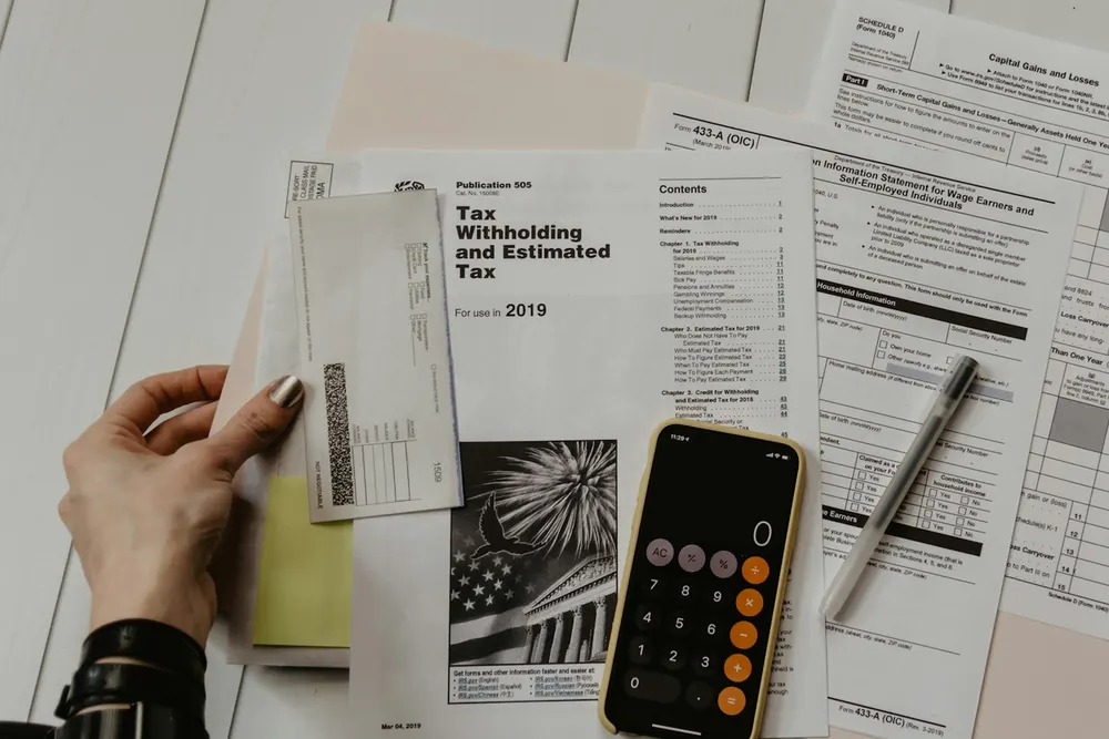 Estimated tax forms, a pen and a calculator laid out on a desk